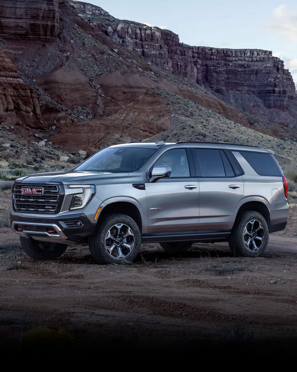 A gray SUV parked on a dirt road under red cliffs