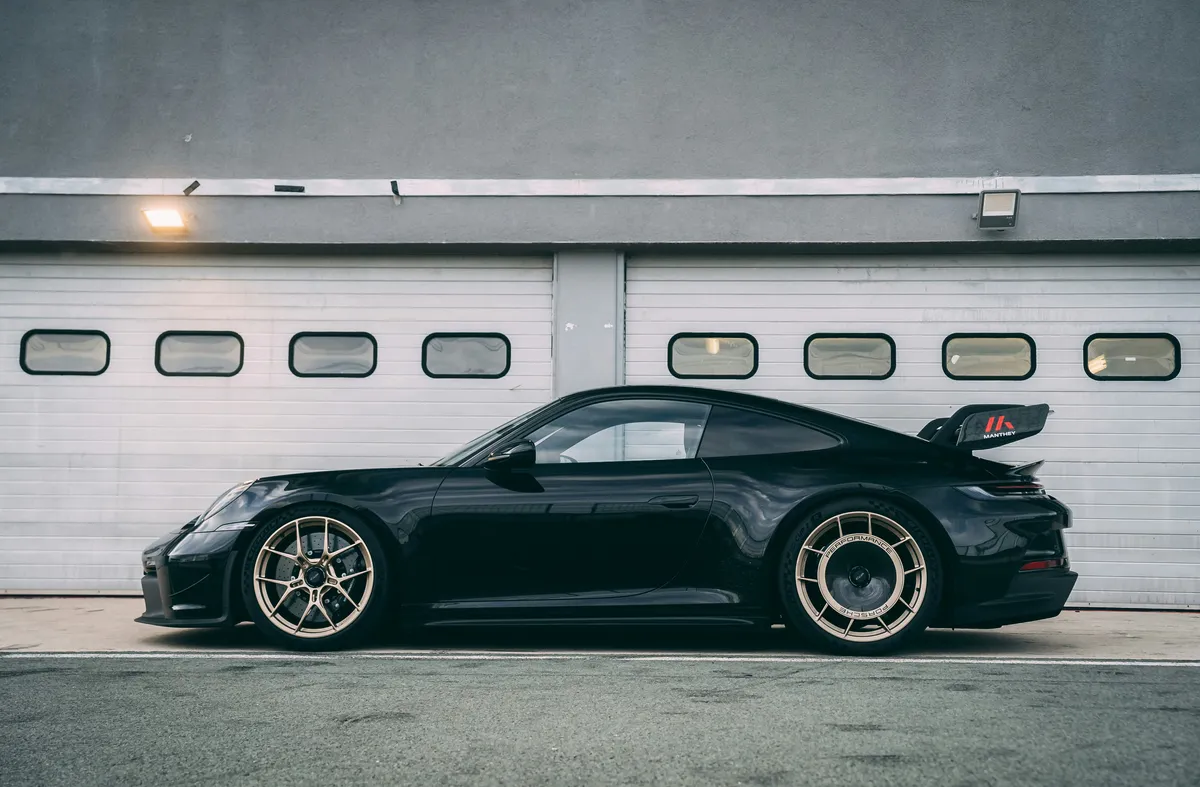 A dark sports car parked in front of a row of garage doors